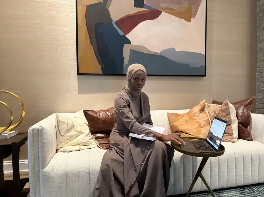 A bookkeeper working on a laptop on a cream sofa in a home office